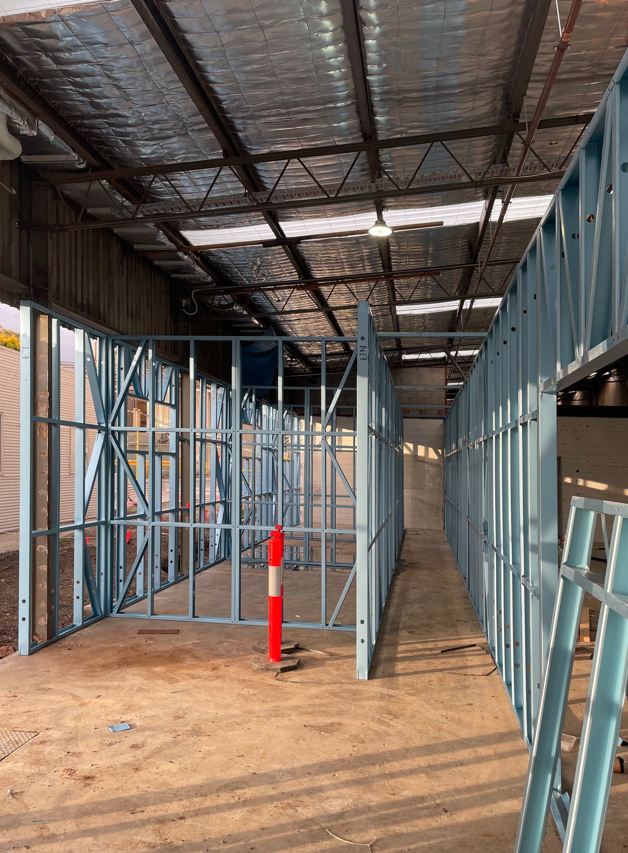 New steel stud wall framing inside a warehouse with an insulated steel roof